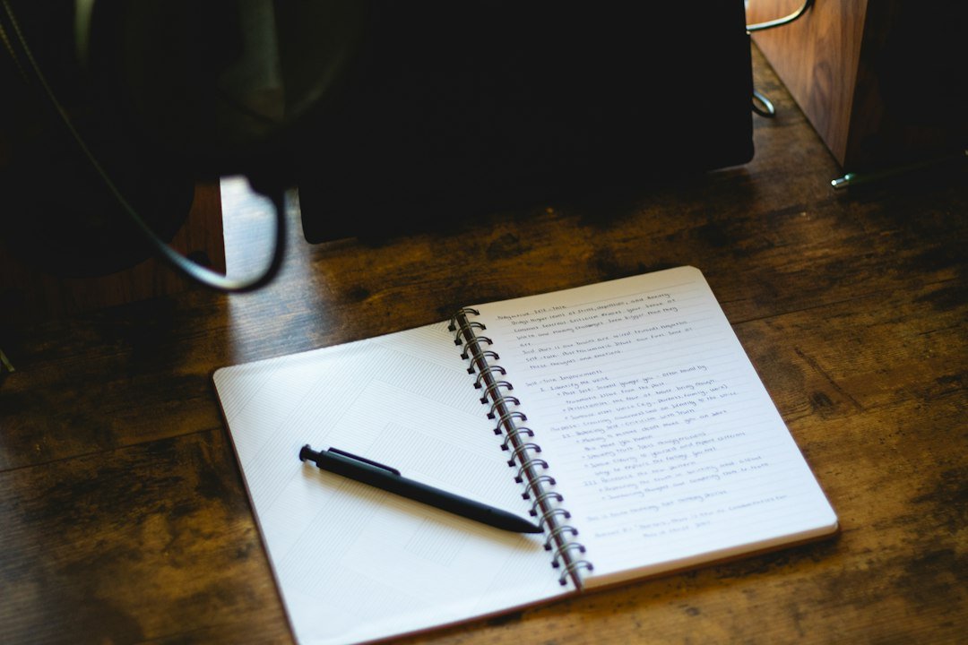 An open notebook with a pen on a wooden desk