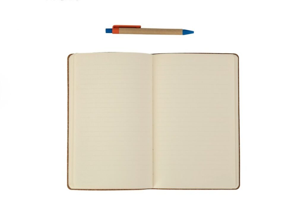 An open notebook with lined pages and a ballpoint pen above it
