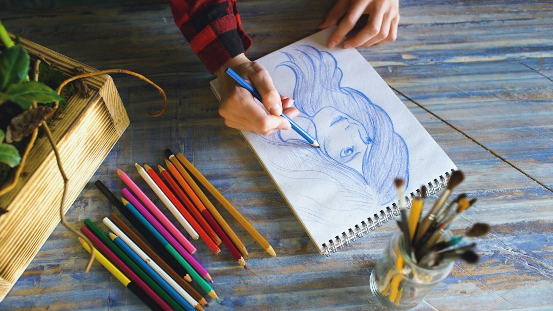 Artist drawing a portrait with colored pencils and brushes