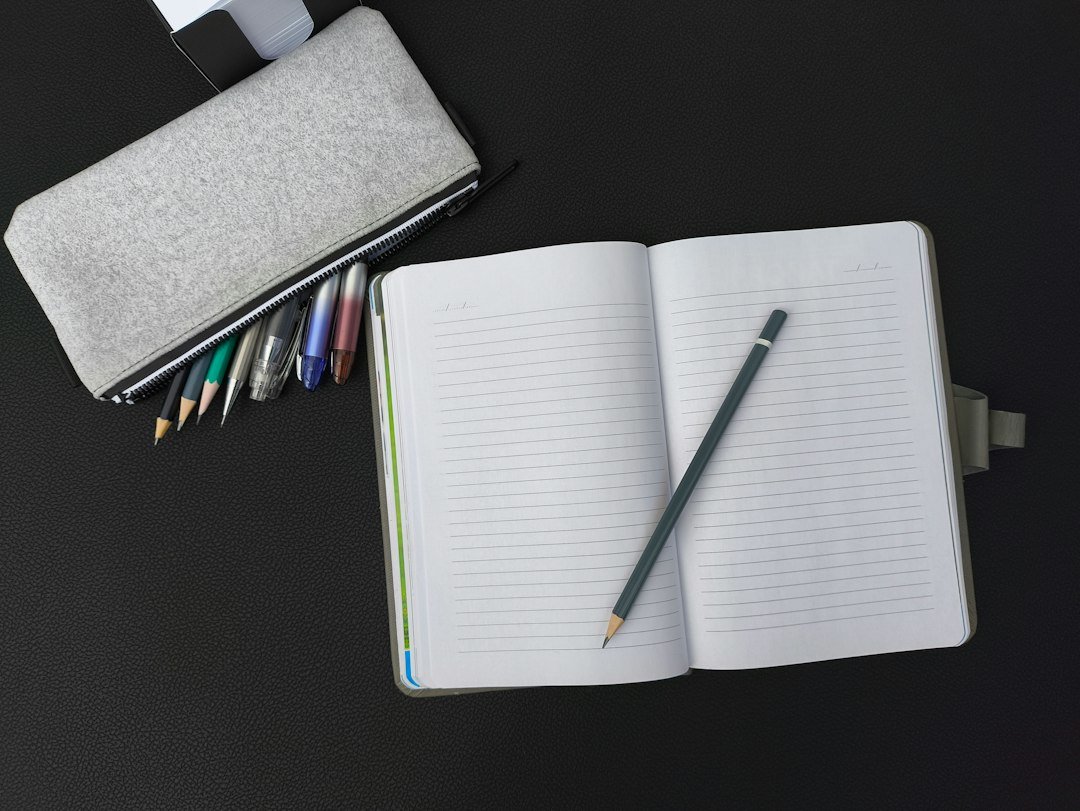 An open notebook with a pen and pencil on a table